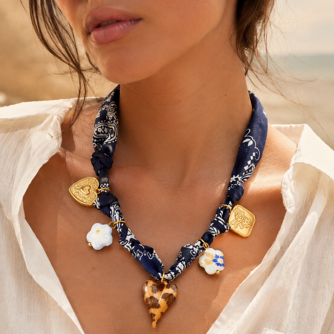 Blue printed scarf necklace with gold-plated heart, flower, leopard heart and ceramic-style charms.
