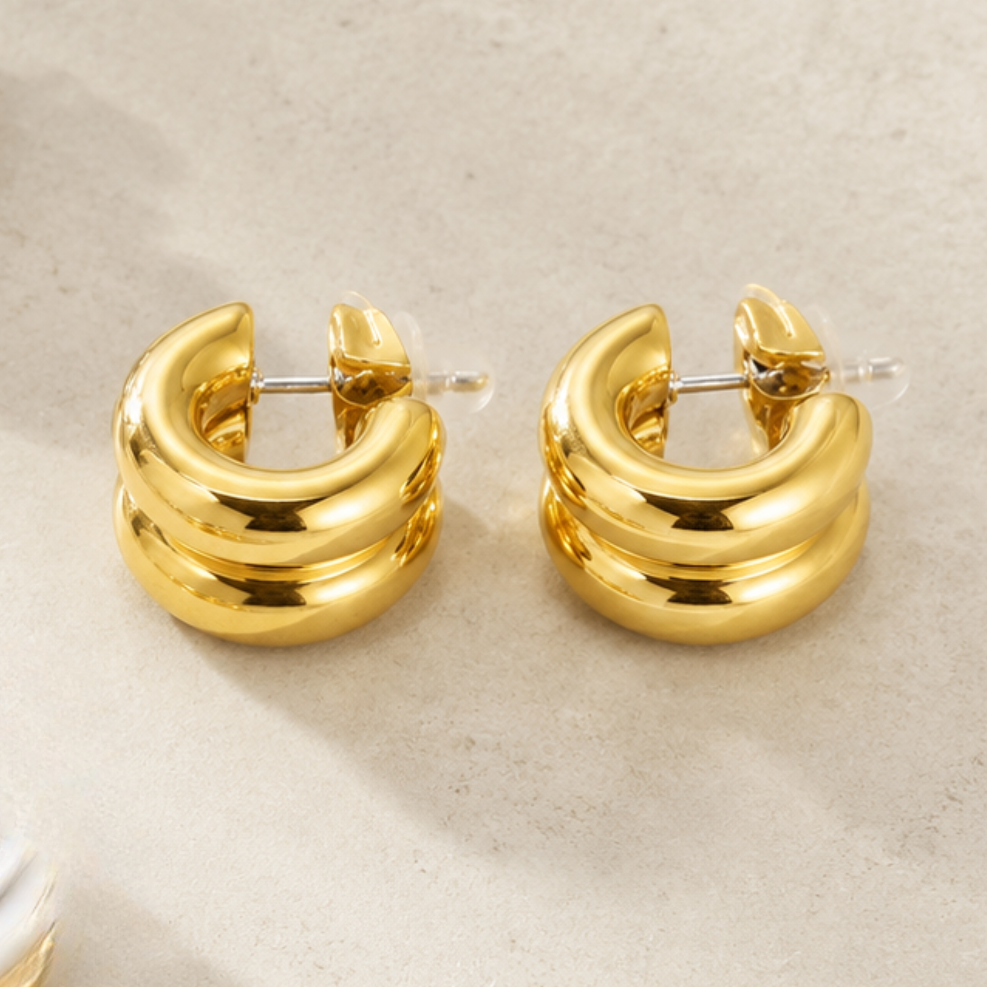 Pair of gold hoop earrings on a beige background