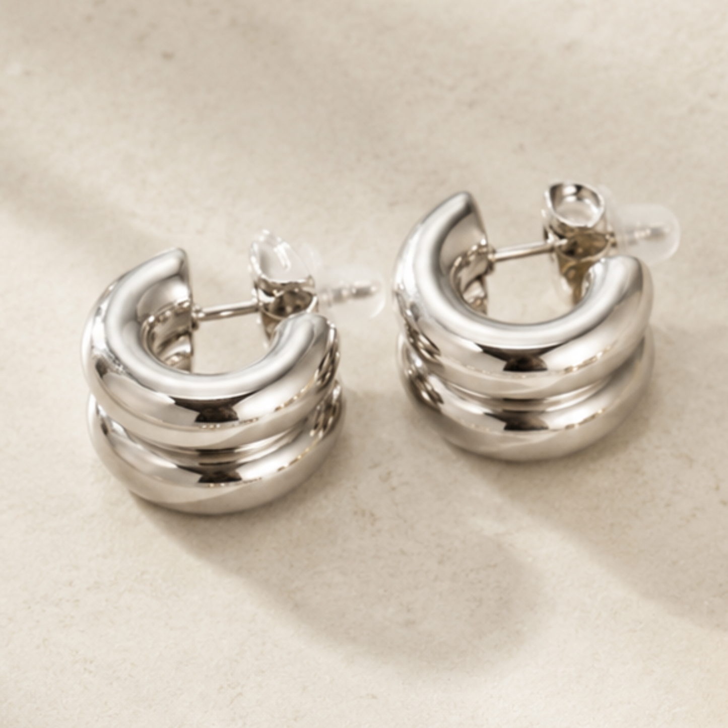 Pair of silver hoop earrings on a beige background